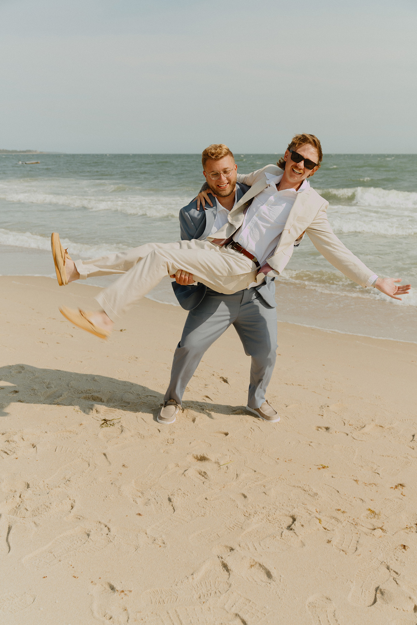 Groom carrying the bride on a beach in New England during a sunset elopement